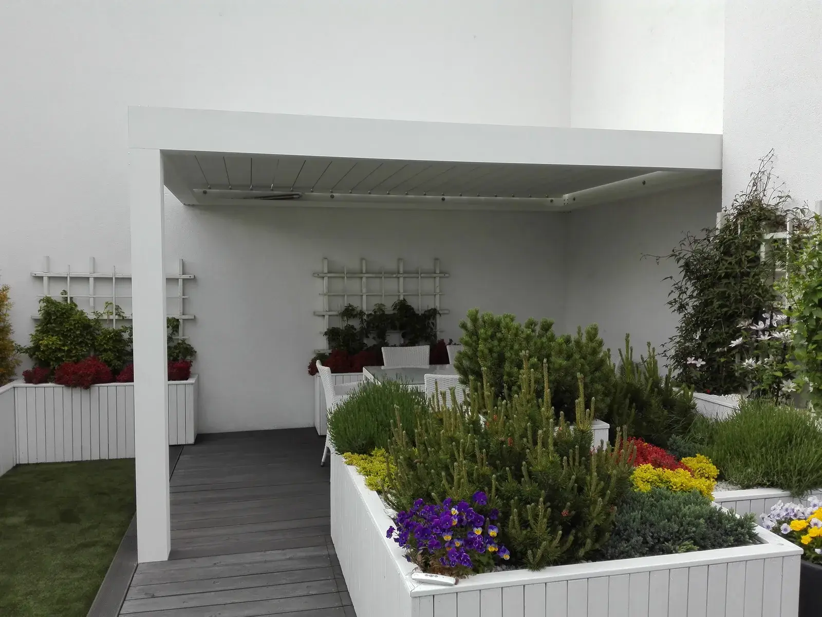 Biela bioklimatická pergola nad terasou s kvetináčmi